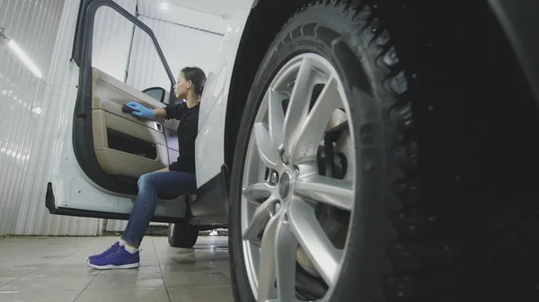 Jonge vrouw in blauw handschoenen is het interieur van de auto voor luxe Suv reinigen — Stockfoto