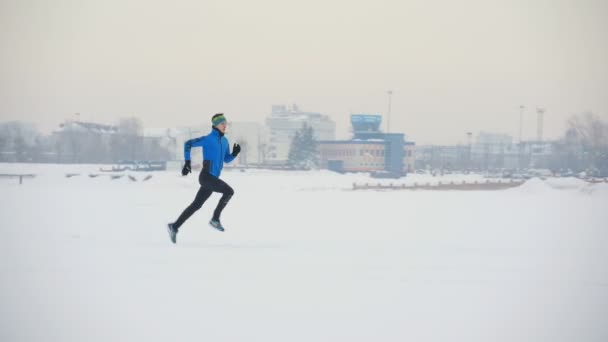 Hombre joven atleta corriendo en invierno al aire libre — Vídeo de stock