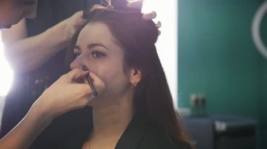 Genç esmer Güzellik Salonu, makyaj yapıyor ve şekillendirme, makyaj sanatçısı Kuaför şekillendirme yapar.