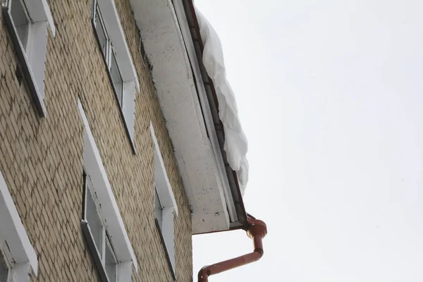 Dangerous snow falls hanging down from the roof — Stock Photo, Image