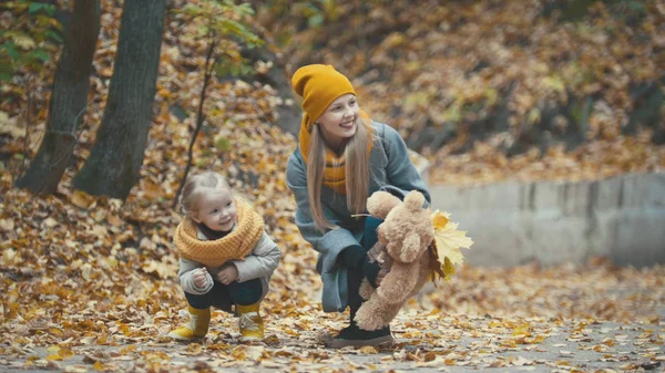 Маленькая блондинка со своей мамой проводит время в осеннем парке — стоковое фото