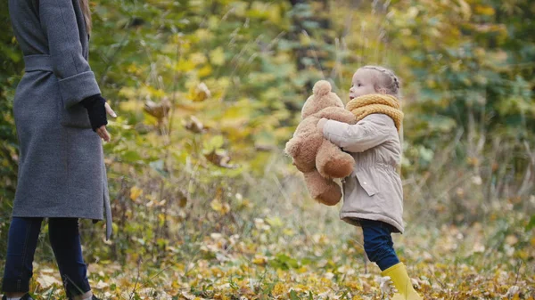 Dochtertje met haar moeder en Teddy Bear wandelen in de herfst park — Stockfoto