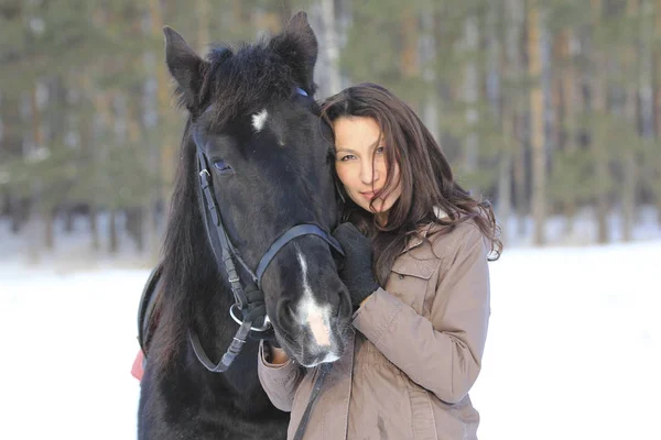 Retrato de uma jovem mulher de cabelo preto abraçando um cavalo — Fotografia de Stock