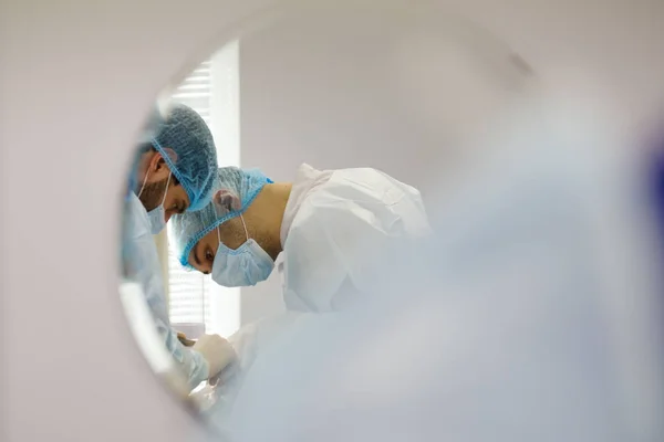 Reflection in the mirror - Doctor dentist and assistant during stomatology operation