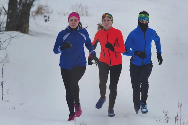 Groep van jonge sporters die technisch in winter bos loopt — Stockfoto