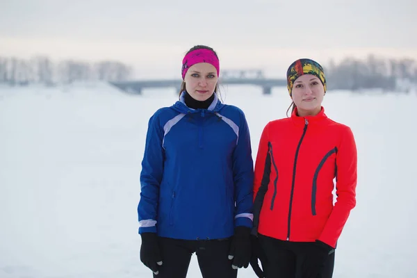Porträtt av en två unga kvinnliga idrottare poserar i vinter isfältet — Stockfoto
