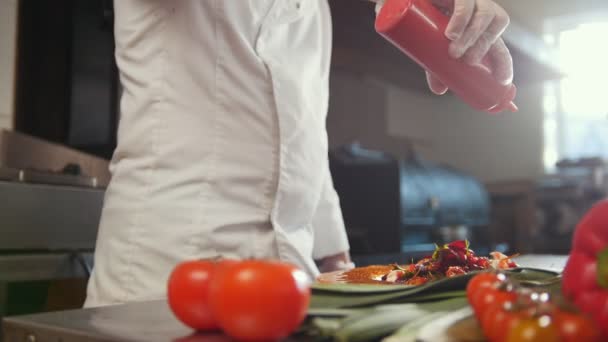 Szakács szolgálja a salátát, hozzá a szósz, friss zöldségek, az előtérben — Stock videók