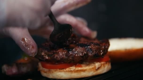 Chef preparing the burger, frying the bun on the grill, putting the tomatoes, meat and sauce — Stock Video