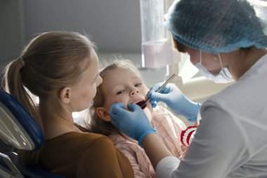 Diş hekimi odasında - doktor anne ile küçük kız kızlar diş inceliyor