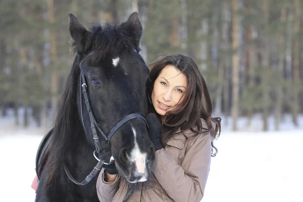 Retrato de uma jovem mulher de cabelo preto abraçando um cavalo — Fotografia de Stock