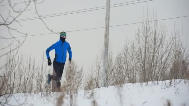 Joven atleta masculino corriendo rápido en invierno a través del campo de hielo nevado — Vídeos de Stock