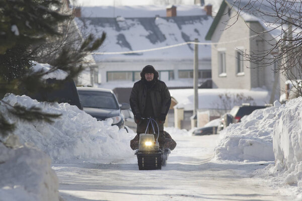 Compact snowmobile - motorcycle towing pulls cargo on snow countryside