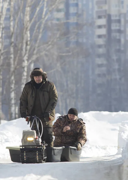 Компактный снегоход для охоты - буксировка мотоцикла тянет двух охотников в солнечной зимней сельской местности — стоковое фото