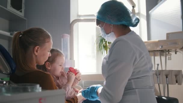 Kleines Mädchen mit Mama im Zahnarztzimmer - Arzt untersucht die Zähne der Mädchen — Stockvideo