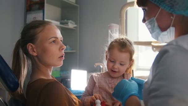 Little girl with mommy in dentist room - conversation with doctor — Stock Video