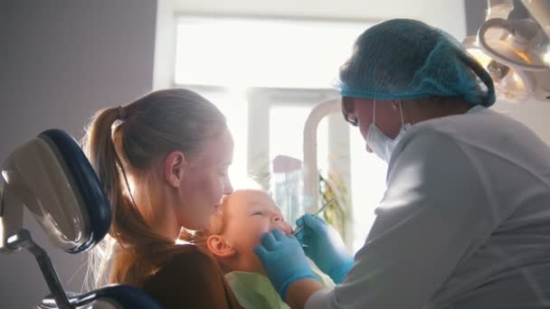 Детская стоматология - стоматолог и маленькая девочка с мамой — стоковое видео