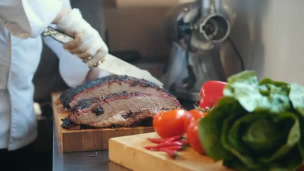 Nedskjæring av et stort stykke røkt kjøtt på et trebord – stockvideo