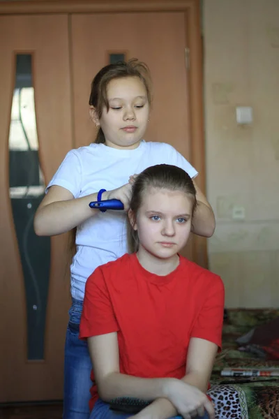 Filles adolescentes sœurs fait des cheveux pour l'autre à la maison — Photo