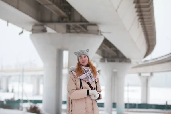 Portret van de jonge vrouw staat onder grote brug, moderne winter stad — Stockfoto