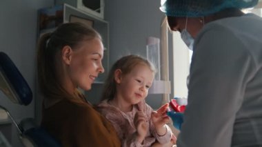 Kız, annesi ve diş hekimi diş ofiste, özel bir oyuncakla danışmanlık stomatologist