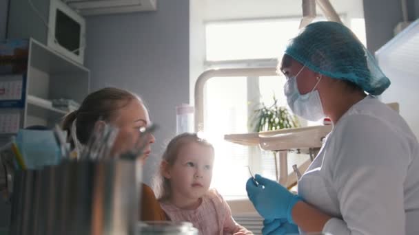 Menina, sua mãe e o dentista no consultório odontológico, o estomatologista consultoria com um brinquedo especial — Vídeo de Stock