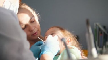 Diş hekimi resepsiyonda kız, stomatologist childs dişler, yaramaz kız gülümseyerek inceliyor