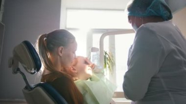 Kız, annesi ve diş hekimi diş office, stomatologist inceleyerek, Doktor sarılma kız