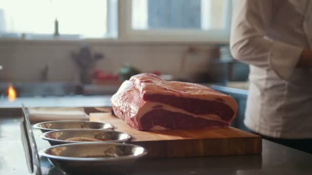 Slakteren lager et stort stykke ferskt, rått kjøtt på et trebord i et kommersielt kjøkken – stockvideo