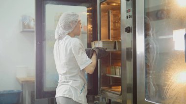 Fırında pişirme üzerinde ticari mutfak - kadın bakes kadın koyar