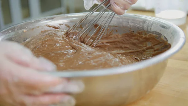 Пекарь смешивает шоколадный крем в металлической миске — стоковое фото