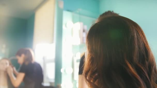 Profesjonalny stylista robi makijaż dla młodej kobiety w gabinecie kosmetycznym — Wideo stockowe