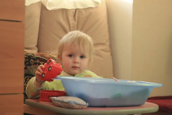 Portrait d'une petite blonde aux yeux bleus avec ses jouets à la maison — Photo