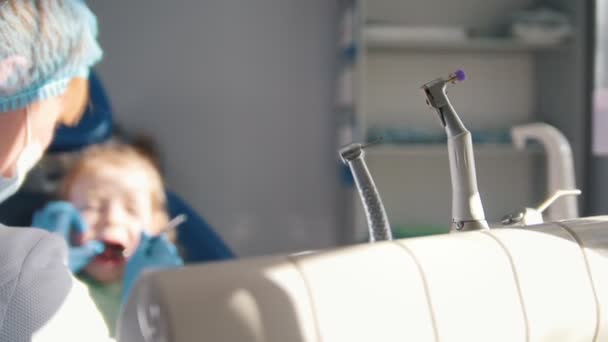 Дівчина на прийомі у стоматолога, стоматолог прибирає і поливає зуби дитини, дівчина посміхається і розмовляє — стокове відео