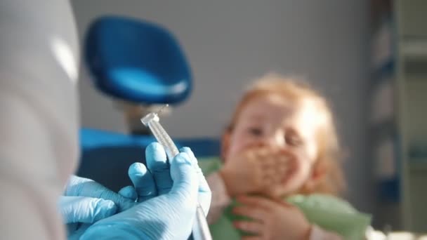 Kleines süßes Mädchen in der Zahnarztpraxis will nicht behandelt werden, wehrt sich und schließt den Mund mit den Händen — Stockvideo