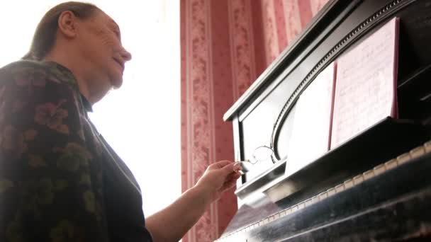フォルテ ピアノの近くメガネで年配の女性の肖像画 — ストック動画