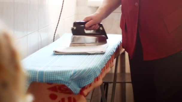 Пожилая женщина гладит одежду дома в ванной комнате — стоковое видео