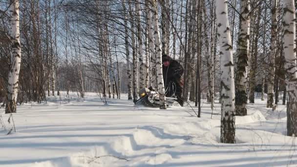 Mann rast mit Mini-Motorschlitten durch tiefe Schneeverwehungen im Wald und manövriert zwischen den Bäumen — Stockvideo