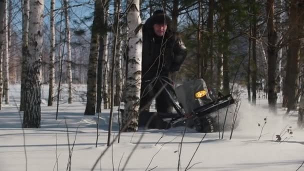 Mutiger Mann manövriert auf Mini-Motorschlitten auf tiefen Schneeverwehungen im Winterwald zwischen den Bäumen — Stockvideo
