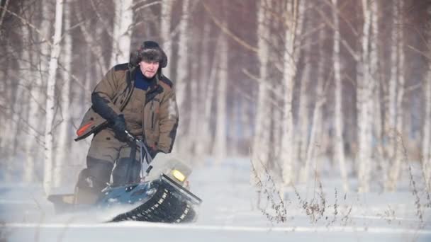 L'uomo supera la neve profonda su una mini motoslitta nella foresta innevata, manovre abili — Video Stock