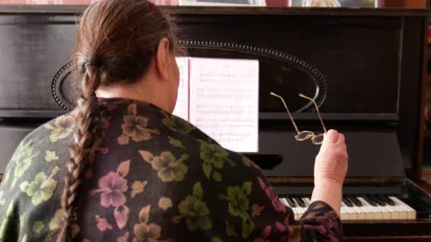 Retrato de uma mulher idosa com óculos perto do piano — Vídeo de Stock