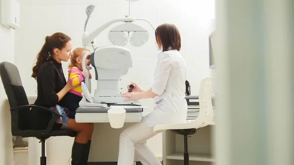 Mother with little daughter in eye clinic - children ophthalmology - optometrist Checks Childs Eye