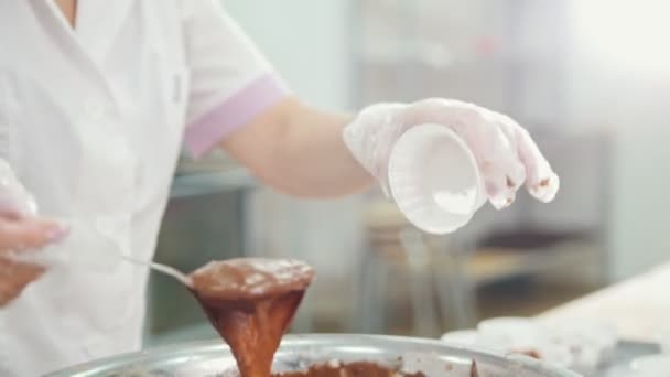 Baker mezcla crema de chocolate en un tazón de metal y hace pasteles — Vídeos de Stock