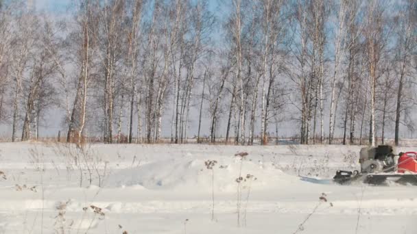 Человек в зимней одежде преодолевает высокий снег на мини-снегоходе и прыгает через дрейф — стоковое видео
