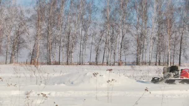 Homme en vêtements d'hiver surmontant la neige sur une mini motoneige et sautant à travers la dérive — Video