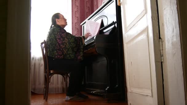 Mujer mayor en casa está empezando a tocar el piano — Vídeo de stock