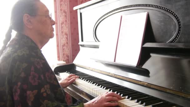 Senior woman in eyeglasses is playing the piano — Stock Video