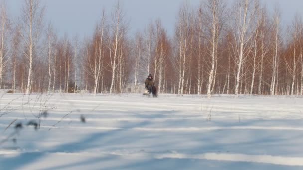 Чоловік в зимовому одязі швидко їде, маневрує і перевозить пасажирів в трейлері міні снігоходів через снігоходи — стокове відео