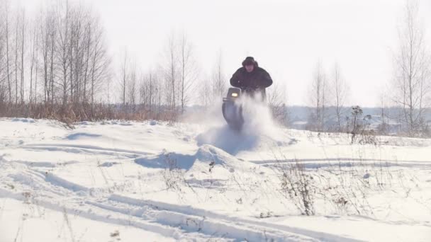 Дорослий чоловік в зимовому одязі швидко їде через глибокий сніг на міні снігоході і долає високі снігові бани — стокове відео