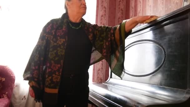 Ηλικιωμένη γυναίκα στο σπίτι σκόνη σκουπίζει στο πιάνο — Αρχείο Βίντεο