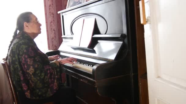 Mujer mayor en gafas está tocando el piano — Vídeos de Stock